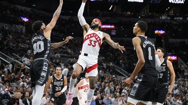 Gary Trent Jr. (33), de los Raptors de Toronto, dispara ante la presión defensiva de Julian Champagnie (30) y la mirada de Victor Wembanyama (1), de los Spurs de San Antonio, durante la segunda mitad del juego de baloncesto de la NBA, el domingo 5 de noviembre de 2023, en San Antonio. (AP Foto/Darren Abate)