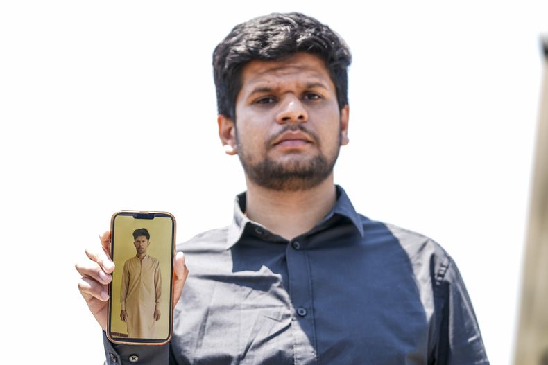 Zohaib Shamraiz muestra una fotografía de su tío Nadeem Muhamm, de 40 años, quien fue reportado como desaparecido, afuera de un campamento de migrantes en Malakasa, al norte de Atenas, Grecia, el lunes 19 de junio de 2023. (AP Foto/Petros Giannakouris)