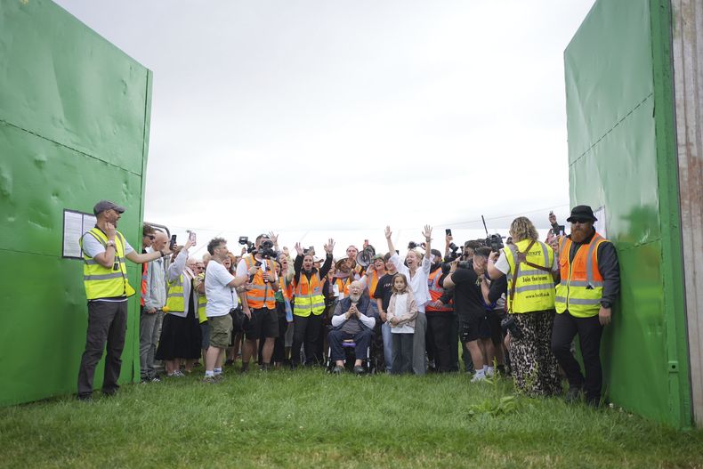 Emily Eavis (centro derecha) y Michael Eavis (centro) reaccionan junto a otros al abrirse las puertas el primer día del Festival de Glastonbury en Worthy Farm, Somerset, Inglaterra, miércoles 25 de junio de 2025. (Yui Mok/PA via AP)