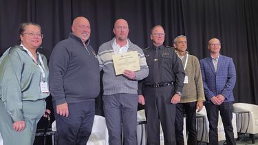 Pete Carlson (tercero desde la izquierda), quien iba a bordo del avión de Delta Air Lines que se volcó el lunes en Toronto, sostiene un certificado de reconocimiento por sus acciones para ayudar a evacuar el avión y ayudar a otros pasajeros, el miércoles 19 de febrero de 2025, en Toronto, Canadá. (AP Foto/John Wawrow)