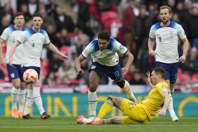 ARCHIVO - El ucraniano Taras Stepanenko (en el piso) pugna por el balón con el inglés Jude Bellingham (centro) en las eliminatorias de la Euro 2024, el 26 de marzo de 2023 en Londres. (AP Foto/Alastair Grant)