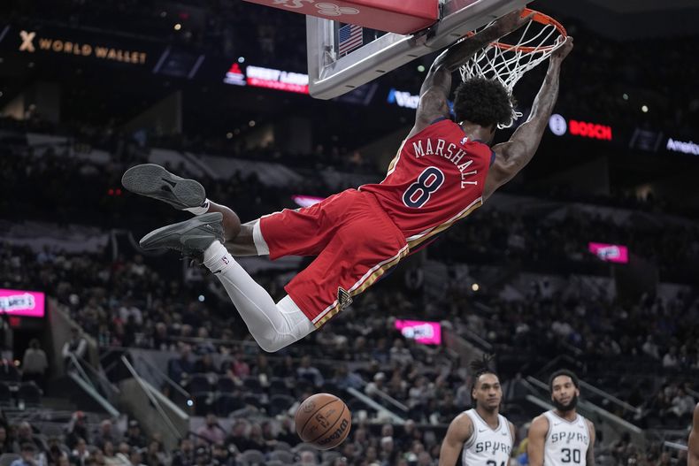 Naji Marshall (8), de los Pelicans de Nueva Orleans, se balancea en el aro después de una clavada en contra de los Spurs de San Antonio, durante la segunda mitad del juego de baloncesto de la NBA, en San Antonio, el domingo 17 de diciembre de 2023. (AP Foto/Eric Gay)