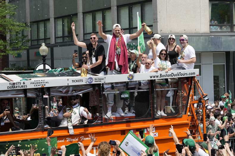 Kristaps Porzingis de los Celtics saluda a la afición portando un medallón del equipo durante los festejos tras el campeonato de la NBA el viernes 21 de junio del 2024. (AP Foto/Michael Dwyer)