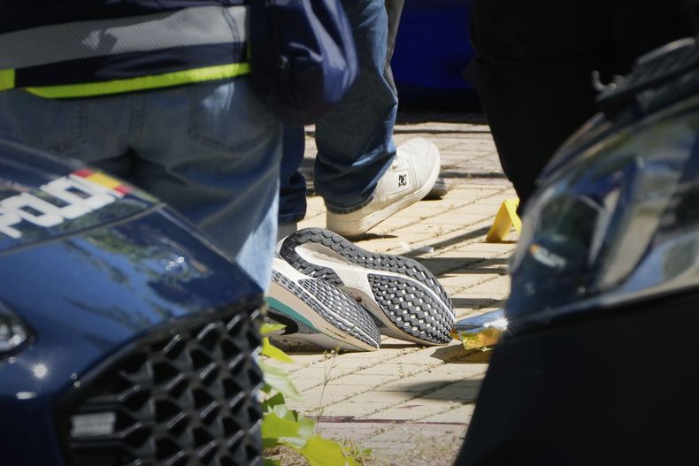 Miembros de la policía judicial trabajan junto al cuerpo de un asesor del expresidente ucraniano Viktor Yanukovich, en el lugar de un tiroteo ante una escuela en la región de Madrid, España, el miércoles 21 de mayo de 2025. (AP Foto/Paul White)