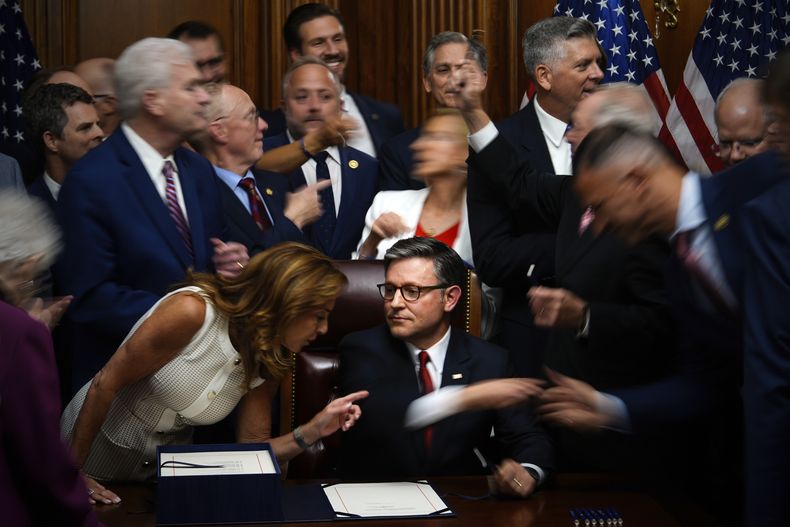 Miembros republicanos del Congreso le dan la mano al presidente de la Cámara de Representantes, Mike Johnson, al fondo, en el centro, después de que firmara el emblemático proyecto de ley de exenciones fiscales y recortes de gastos del presidente Donald Trump, el jueves 3 de julio de 2025, en el Capitolio, Washington. (AP Foto/Julia Demaree Nikhinson)