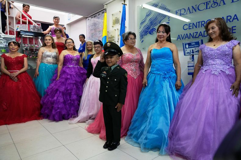 Un niño acompaña a Rosalba Casas, a la derecha, y a otras mujeres que nunca tuvieron una fiesta tradicional de 15 años durante una celebración de quinceañera organizada por la fundación Sueños Hechos en Bogotá, Colombia, el viernes 24 de octubre de 2025. (Foto AP/Fernando Vergara)