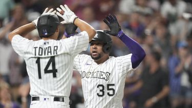 Ezequiel Tovar, izquierda, de los Rockies de Colorado, felicita a Elias Diaz popr su grand slam ante el relevista de los Angelinos de Los Ángeles Chris Devenski durante la octava entrada del juego de béisbol, el viernes 23 de junio de 2023, en Denver. (AP Foto/David Zalubowski)
