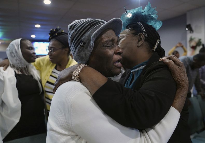 Marie Guillou, en primer plano a la izquierda, abraza a una feligresa en la Primera Iglesia Evangélica Haitiana de Springfield, el domingo 26 de enero de 2025, en Springfield, Ohio. (AP Foto/Jessie Wardarski)