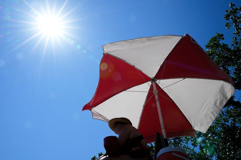El sol brilla sobre una salvavidas mientras vigila una playa en el lago Harriet durante una alerta por calor extremo, el lunes 13 de julio de 2026, en Minneapolis. (AP Foto/Ellen Schmidt)