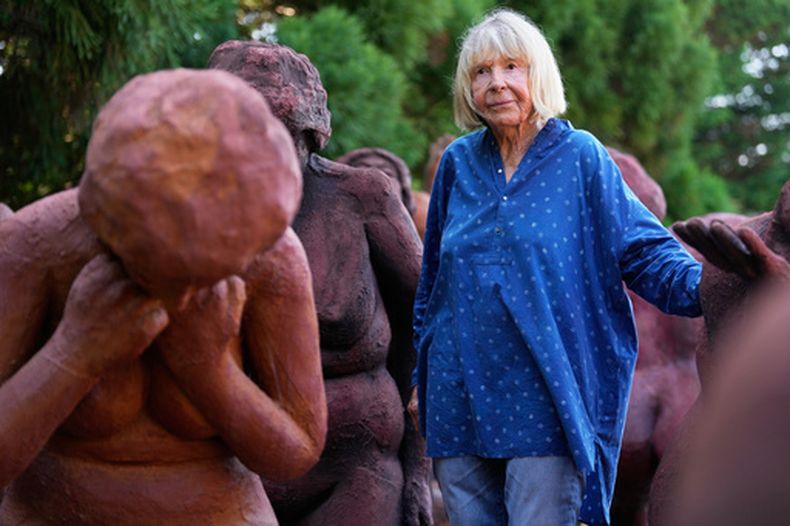 La artista Suse Lowenstein, cuyo hijo, Alex, murió en el atentado contra el vuelo 103 de Pan Am sobre Lockerbie, Escocia, posa entre las figuras que conforman su escultura Dark Elegy en su patio trasero en Montauk, Nueva York, el miércoles 19 de agosto de 2026. (AP Foto/Seth Wenig)