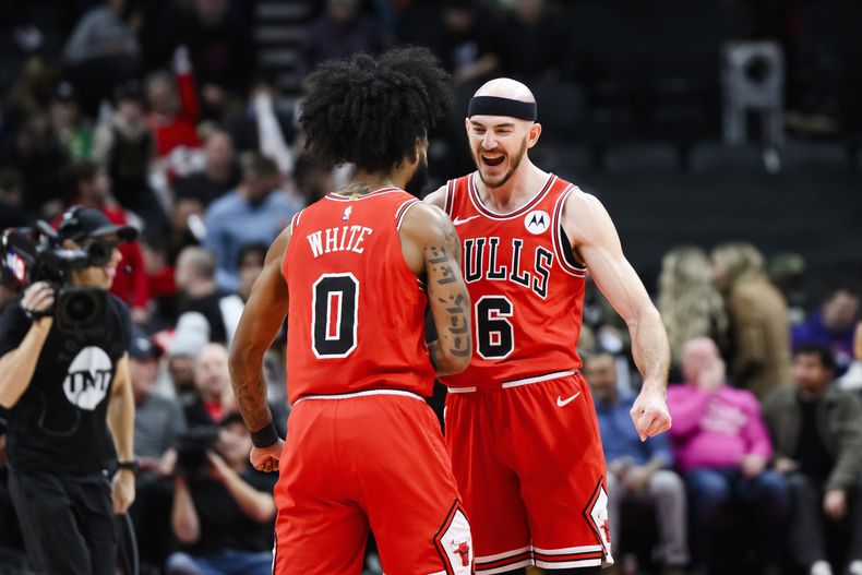 Los escoltas de los Bulls de Chicago Alex Caruso (6) y Coby White (0) celebran después de derrotar a los Raptors de Toronto en el partido de baloncesto de la NBA en Toronto, el jueves 18 de enero de 2024. (Christopher Katsarov/The Canadian Press vía AP)