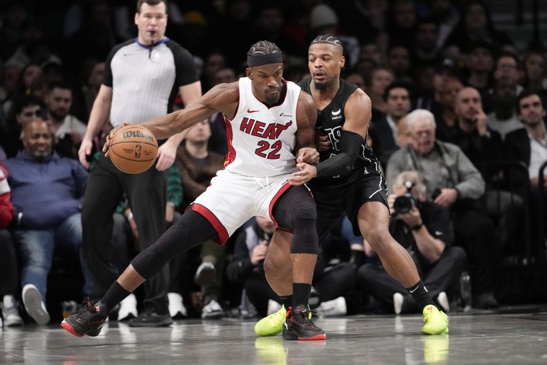 Jimmy Butler (22), del Hear de Miami, protege el balón y busca pasar a Dennis Smith Jr., de los Nets de Brooklyn, durante la segunda mitad del juego de baloncesto de la NBA, el lunes 15 de enero de 2024, en Nueva York. (AP Foto/Mary Altaffer)