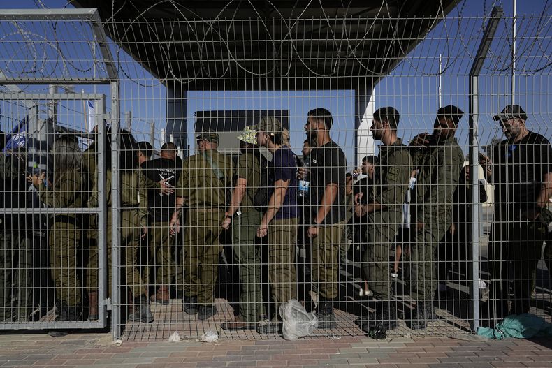 En esta imagen de archivo, soldados israelíes esperan en la puerta de la base militar Sde Teiman mientras la gente se manifiesta a favor de los soldados interrogados por supuestos abusos a detenidos, el 29 de julio de 2024. (AP Foto/Tsafrir Abayov, archivo)