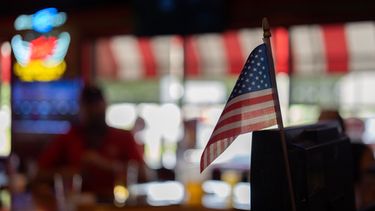 Una bandera estadounidense, en la caja registradora del bar Frickers en Springfield, Ohio, el 30 de septiembre de 2026, mientras los miembros del sindicato UAW Local 402 toman un trago en el último día de la antigua Navistar en su planta de Springfield. (AP Foto/Carolyn Kaster)