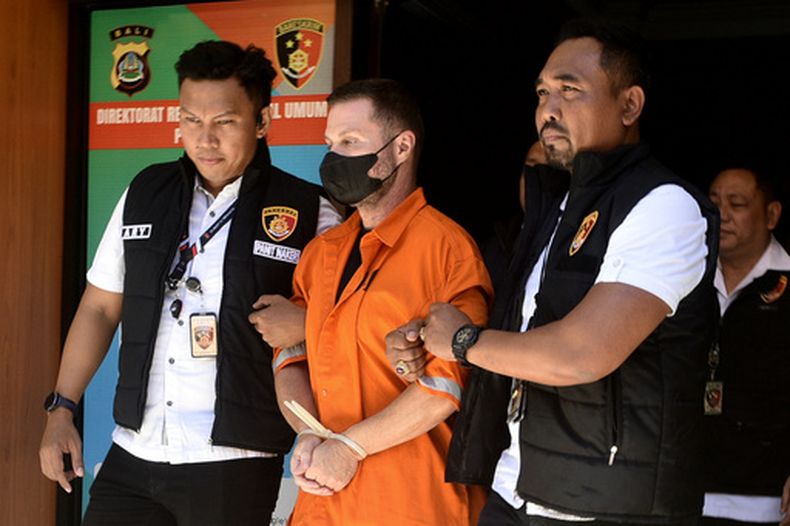 Un escocés identificado como Steven Lyons, descrito como una figura de alto nivel de una red criminal internacional, centro, es escoltado por agentes en el cuartel general de la policía regional en Denpasar, Bali, Indonesia, el martes 31 de marzo de 2026. (AP Foto)