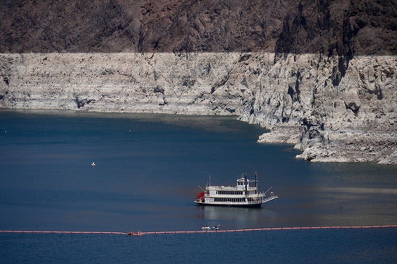 Un barco de paletas en el lago Mead se encuentra muy por debajo de la marca de minerales claros —similar a la línea de suciedad en una bañera— que evidencia la pérdida de agua, el viernes 7 de agosto de 2026, cerca de la presa Hoover y de Boulder City, Nevada. (AP Foto/Ty ONeil)