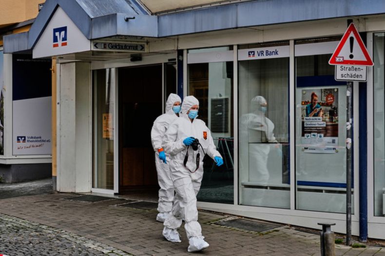 Agentes de la policía de investigación caminan frente a una sucursal bancaria tras una toma de rehenes en Sinzig, Alemania, el viernes 8 de mayo de 2026. (Foto AP/Michael Probst)