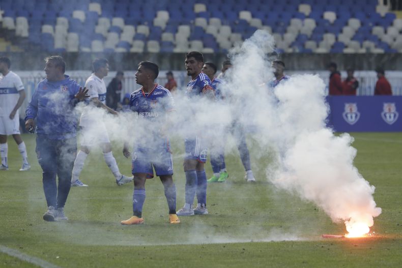 Jugadores del club Universidad de Chile salen de la cancha mientras una bengala lanzada por hinchas arde en el campo durante un partido contra Universidad Católica por el torneo local en el Estadio Ester Roa de Concepción, Chile, el domingo 30 de abril de 2023. El partido fue suspendido luego que los fanáticos lanzaron fuegos artificiales y bengalas a la cancha. (Eduardo Fortes/Photosport ) CHILE OUT