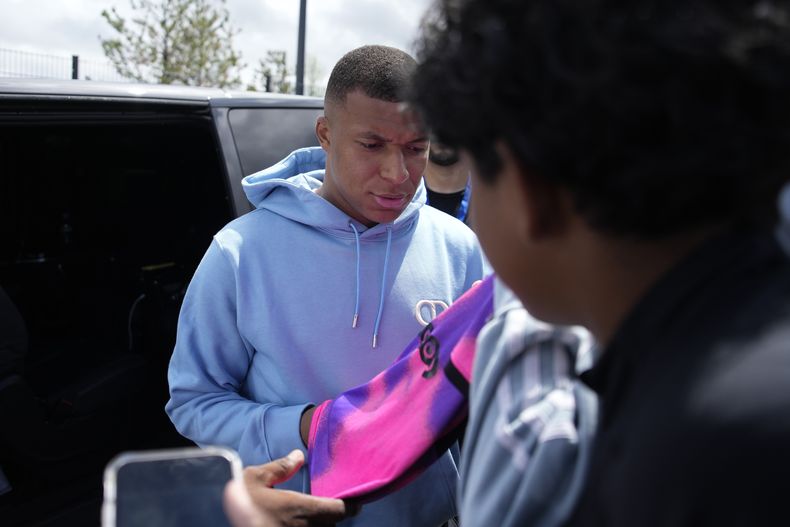 Kylian Mbappé del Paris Saint-Germain firma autógrafos a la salida de la ciudad deportiva del club, el viernes 28 de julio de 2023, en las afueras de París. (AP Foto/Lewis Joly)