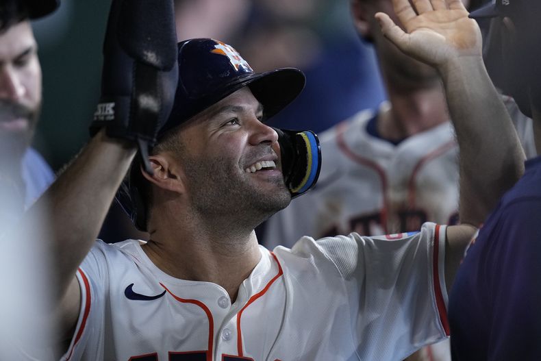 José Altuve, de los Astros de Houston, celebra en el dugout después de anotar con un doble de dos carreras de Kyle Tucker durante la séptima entrada del juego de béisbol contra los Rangers de Texas, el sábado 13 de abril de 2024, en Houston. (AP Foto/Kevin M. Cox)