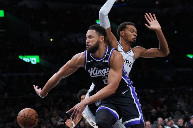 El guardia de los Kings de Sacramento, Ben Simmons (25), se abre paso ante el delantero de los Spurs de San Antonio, Victor Wembanyama (1), durante la primera mitad de un partido de básquetbol de pretemporada de la NBA en San Antonio, el viernes 16 de octubre de 2026. (Foto AP/Eric Gay)