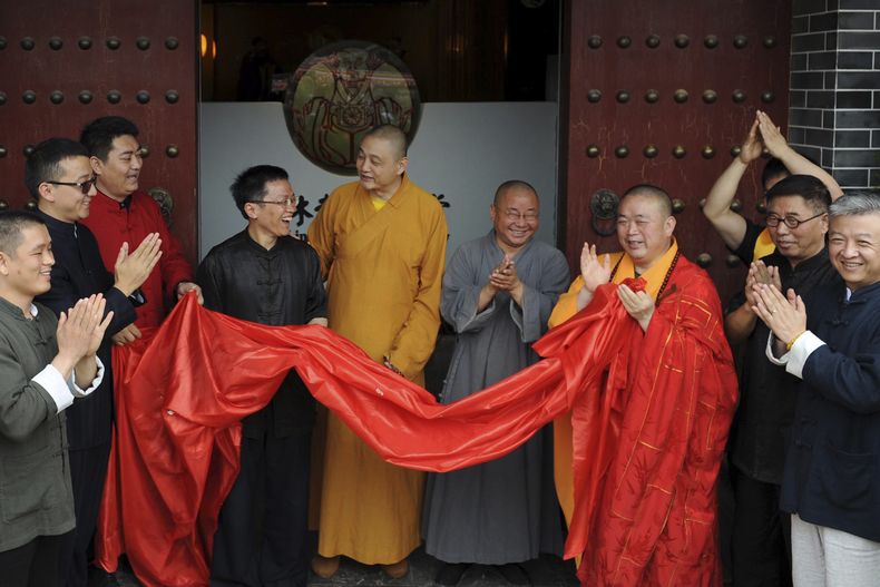 Foto del 28 de junio del 2015 que muestra a Shi Yongxin, tercero de la derecha en bata amarilla y roja, abad del Templo Shaolin, en la inauguración de un centro en Xian en la provincia de Shaanxi en China. (Chinatopix via AP)