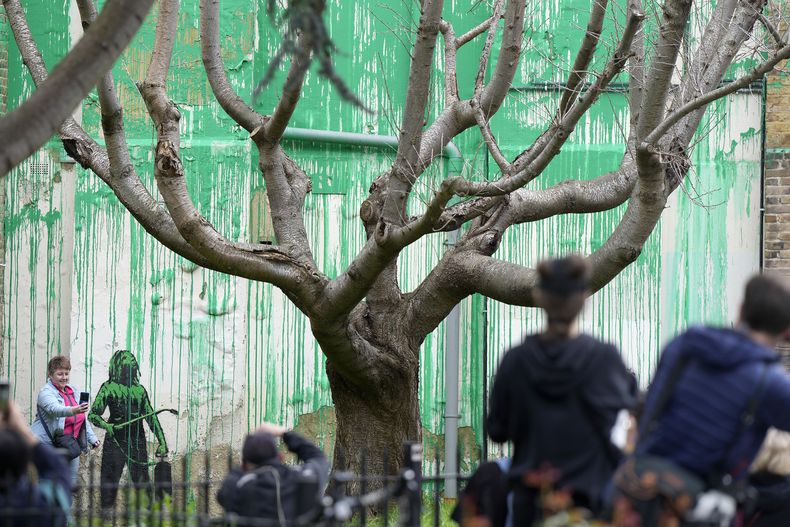 Personas miran un nuevo mural de Banksy en una pared en Londres, el lunes 18 de marzo de 2024. Un nuevo mural de Banksy en el vecindario de Finsbury Park atrajo multitudes a una calle de Londres el lunes, incluso antes de que el esquivo artista de graffiti confirmara que la obra era suya. (Foto AP/Alastair Grant)
