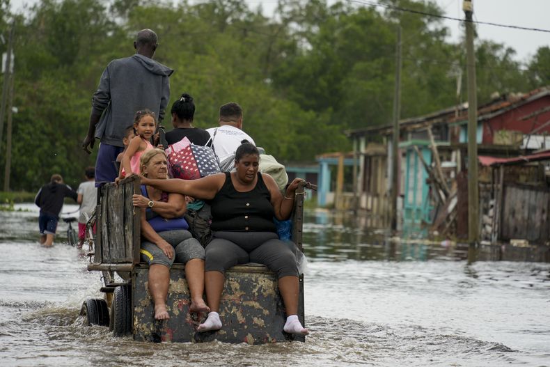 Los residentes recorren una calle inundada en un carro tirado por caballos luego del paso del huracán Rafael por Batano, Cuba, el jueves 7 de noviembre de 2024. (Foto AP/Ramón Espinosa)