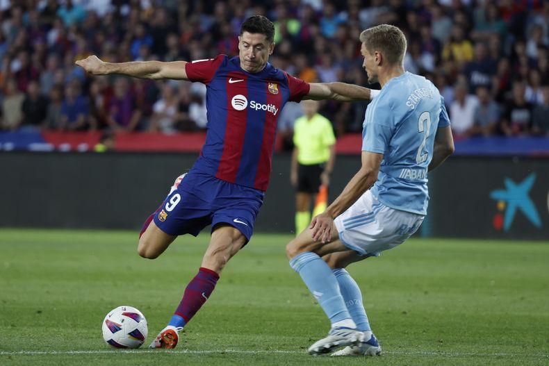 Robert Lewandowski del Barcelona se prepara para disparar el balón frente a Carl Starfelt del Celta de Vigo en el encuentro de la liga española en el Estadio Olímpico en Barcelona el sábado 23 de septiembre del 2023. (AP Foto/Joan Monfort)