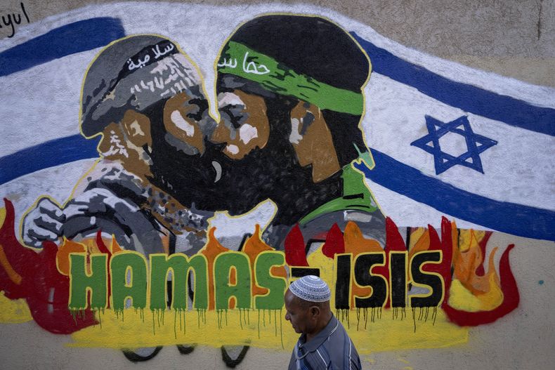 Un hombre pasa por delante de un grafiti reciente que equipara a Hamás con ISIS, en Tel Aviv, Israel, el 30 de octubre de 2023. El 7 de octubre, más de 1.400 personas fallecieron, en su mayoría civiles israelíes, y unas 240 fueron capturadas en un ataque transfronterizo sin precedentes lanzado por insurgentes de Hamás desde la Franja de Gaza. (AP Foto/Oded Balilty)