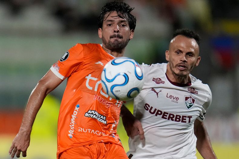 Juan Perdomo, de Deportivo La Guaira, y Rene Rodrigues, de Fluminense de Brasil, persiguen un balón durante un partido de la Copa Libertadores, el martes 7 de abril de 2026 (AP Foto/Ariana Cubillos)