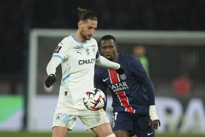 Adrien Rabiot (izquierda) del Olympique de Marsella disputa el balón con Willian Pacho del Paris Saint Germain en el partido de la liga francesa, el domingo 16 de marzo de 2025. (AP Foto/Christophe Ena)