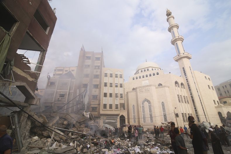 Los palestinos inspeccionan los daños del edificio destruido después de los ataques aéreos israelíes en Khan Younis, Franja de Gaza, el martes 10 de octubre de 2023. Los ataques tienen lugar luego del asalto de Hamas en Israel el fin de semana. (Foto AP/Hatem Ali)