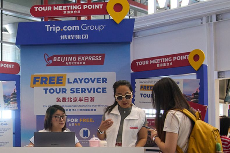 Trabajadoras atienden a una viajera en un puesto de promoción de la agencia de viajes Trip.com en Beijing, el 15 de junio de 2025. (AP Foto/Andy Wong)
