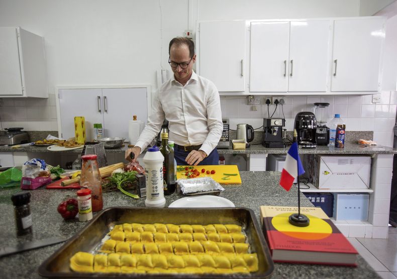 Paul-Bertrand Barets, embajador francés en Zimbabue, prepara un platillo en la cocina de la sede diplomática en Harare, Zimbabue, el miércoles 16 de marzo de 2025, para un concurso de cocina entre diversos diplomáticos extranjeros. (AP Foto/Aaron Ufumeli)