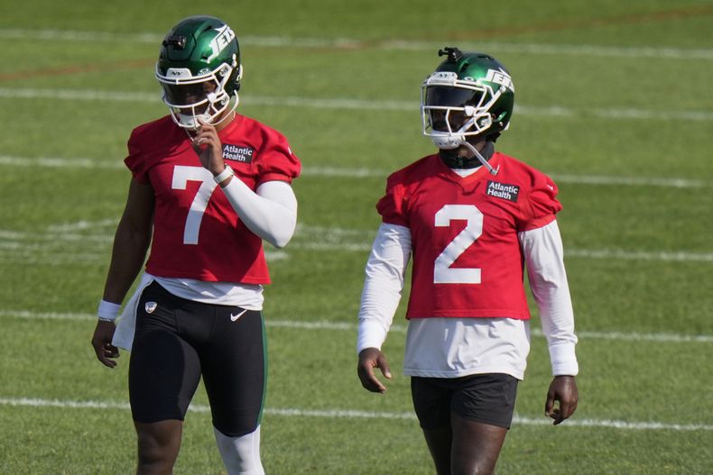Justin Fields (7) y Tyrod Taylor (2), quarterbacks de los Jets de Nueva York, caminan en el campo durante un ejercicio en el campamento de entrenamiento del equipo de la NFL, el jueves 24 de julio de 2025, en Florham Park, Nueva Jersey. (AP Foto/Frank Franklin II)