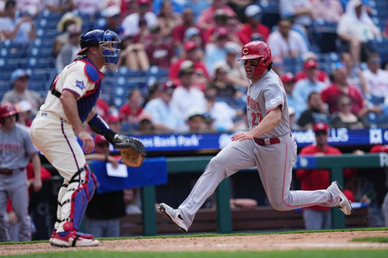 Sal Stewart, derecha, de los Rojos de Cincinnati, anota carrera ante la mirada de J.T. Realmuto, receptor de los Filis de Filadelfia, durante la séptima entrada del juego de béisbol de Grandes Ligas del miércoles 20 de mayo de 2026, en Filadelfia. (AP Foto/Matt Rourke)