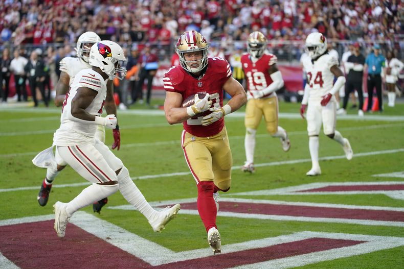 Christian McCaffrey, centro, running back de los 49ers de San Francisco, atrapa un pase de anotación en contra de los Cardinals de Arizona durante la primera mitad del partido de la NFL, el domingo 17 de diciembre de 2023, en Glendale, Arizona. (AP Foto/Matt York)