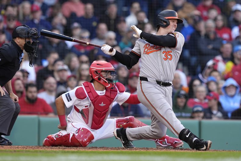 Adley Rutschman de los Orioles de Baltimore le da seguimiento a su sencillo remolcador frente a Reese McGuire de los Medias Rojas de Boston en la séptima entrada del juego del martes 9 de abril del 2024. (AP Foto/Michael Dwyer)