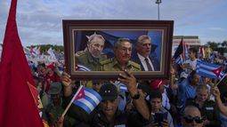 ARCHIVO - Una persona lleva en una marcha un cuadro con una imagen compuesta de Fidel Castro, Raúl Castro y del presidente de Cuba, Miguel Díaz-Canel, en la plaza de la Revolución en La Habana, el 1 de mayo de 2025. (AP Foto/Ramon Espinosa, Archivo)