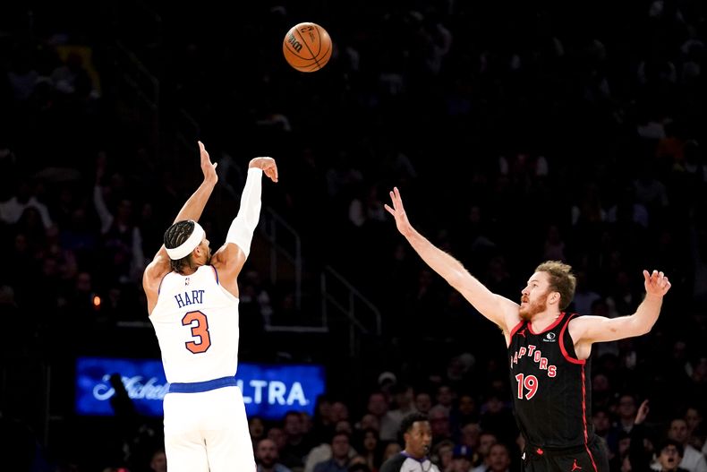 Josh Hart (3), de los Knicks de Nueva York, lanza un triple ante el intento defensivo de Jakob Poeltl (19), de los Raptors de Toronto, durante la segunda mitad del juego de baloncesto de la NBA en Nueva York, el lunes 11 de diciembre de 2023. (AP Foto/Peter K. Afriyie)