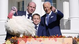 El presidente Joe Biden, derecha, señala a lo lejos junto a John Zimmerman, izquierda, presidente de la Federación Nacional de Pavos; su hijo Grant Zimmerman, al centro, y el pavo nacional del Día de Acción de Gracias, de nombre Peach, durante una ceremonia de indulto en la Casa Blanca, el lunes 25 de noviembre de 2024, en Washington. (AP Foto/Susan Walsh)