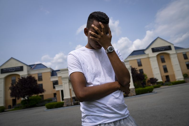 Mohamed, de 19 años y que huyó de la persecución política en Mauritania, posa para una foto ocultando su rostro para proteger su identidad, en el exterior del hotel Crossroads, antes de una entrevista de trabajo, el 22 de mayo de 2023, en Newburgh, Nueva York. Mohamed es uno de los alrededor de los 400 migrantes extranjeros que la ciudad ha alojado este mes en un reducido número de hoteles en otras partes del estado para aliviar la presión sobre su saturado sistema de albergues para gente sin hogar. (AP Foto/John Minchillo)