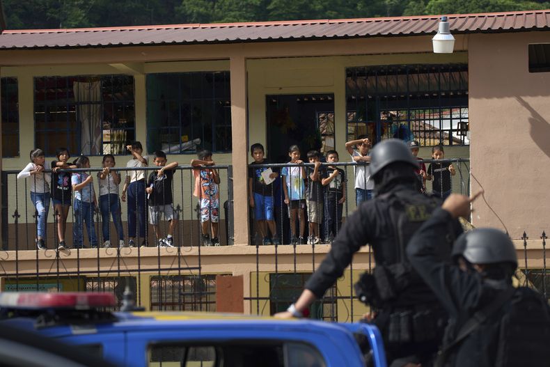 Estudiantes observan desde el balcón de su escuela a un convoy con policías que participan en un operativo contra presuntos narcotraficantes en La Mesilla, Guatemala, cerca de la frontera con México, el miércoles 30 de julio de 2025. (AP Foto/Moisés Castillo)