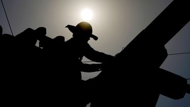 ARCHIVO – Un trabajador revisa el cableado eléctrico bajo el sol de la mañana, el 12 de julio de 2024, en Phoenix. (AP Foto/Matt York, Archivo)