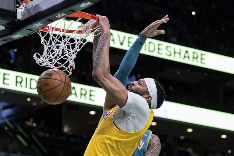 Anthony Davis, de los Lakers de Los Ángeles, clava el balón, mientras recibe una falta de Miles Bridges, de los Hornets de Charlotte, durante la segunda mitad del juego de baloncesto de la NBA, el lunes 5 de febrero de 2024, en Charlotte, Carolina del Norte. (AP Foto/Jacob Kupferman)
