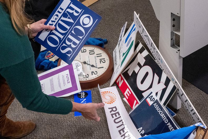 ARCHIVO - La reportera del Washington Post Tara Copp guarda las placas identificativas de diversos medios de comunicación mientras ella y otros miembros de la prensa recogen sus pertenencias en la zona de prensa del Pentágono el 15 de octubre de 2025, en Washington. (AP Foto/Kevin Wolf/Archivo)