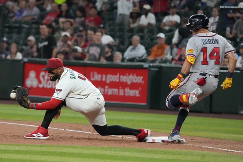 El hondureño Mauricio Dubón, de los Bravos de Atlanta, vence el tiro al dominicano Carlos Santana, de los Diamondbacks de Arizona,para embasarse el jueves 2 de abril de 2026 (AP Foto/Rick Scuteri)