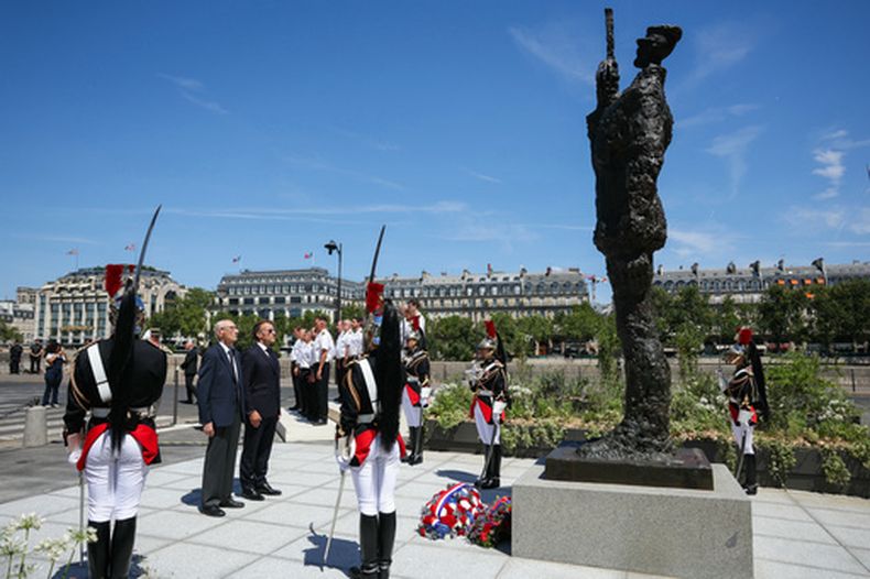 El presidente francés Emmanuel Macron (centro-derecha) con Charles Dreyfus – nieto de Alfred Dreyfus – frente a la estatua de Alfred Dreyfus, en París, el 12 de julio del 2026. (Thomas Samson/Pool Photo via AP)