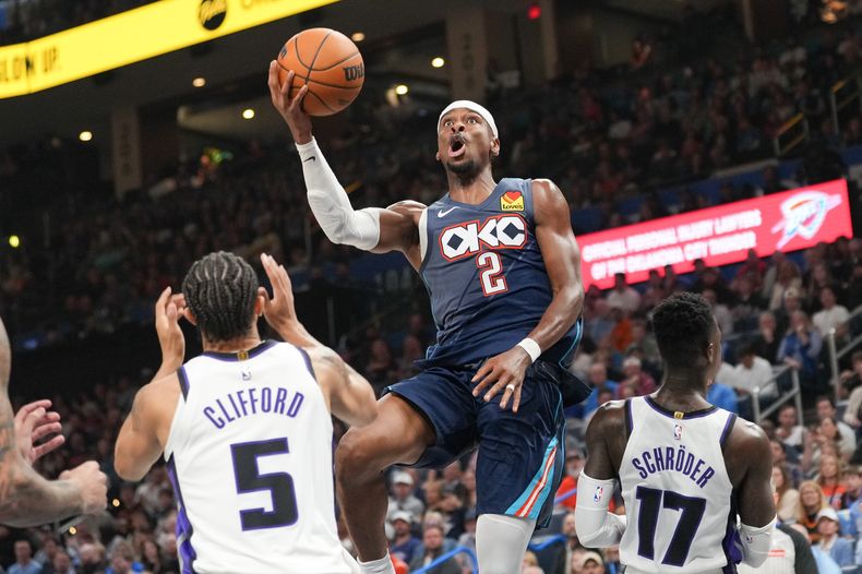 El base del Thunder de Oklahoma City Shai Gilgeous-Alexander lanza sobre Nique Clifford y Dennis Schröder de losKings de Sacramento el miércoles 19 de noviembre del 2025. (AP Foto/Kyle Phillips)